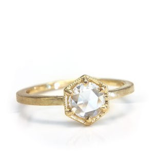 A rose-cut diamond glows in a geometric setting atop a textured band of gleaming gold in this soft and elegant design from the Lumiere Bridal Collection.