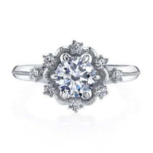Scattered brilliant diamonds set in an open halo, and finished with intricate milgrain detailing create this stunning vintage inspired design from the Hera Bridal collection