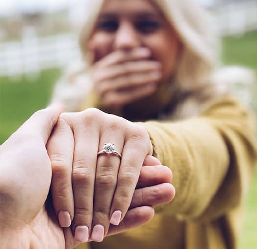 Woman holing mans hand and displays engagement ring