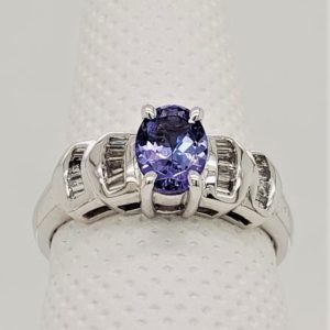 14kt White Gold Tanzanite and Diamond Ring. 7x5 Oval Tanzanite with Channel Set Baguette Set Diamonds. *This item is clearance and is sold as is. This item is being sold in store as well as on the website. Availability is subject to change. Items from clearance cannot be refunded and are exchange only.