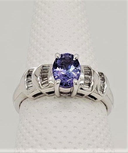 14kt White Gold Tanzanite and Diamond Ring. 7x5 Oval Tanzanite with Channel Set Baguette Set Diamonds. *This item is clearance and is sold as is. This item is being sold in store as well as on the website. Availability is subject to change. Items from clearance cannot be refunded and are exchange only.