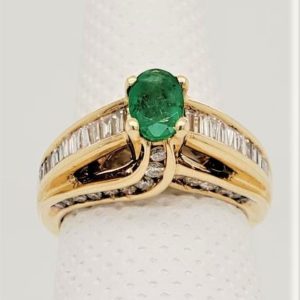 Pre-owned Oval Emerald Set in 14k Yellow Gold with .67ctw Baguettes on shoulders with Round Diamonds Channel Set on Sides. *This item is clearance and is sold as is. This item is being sold in store as well as on the website. Availability is subject to change. Items from clearance cannot be refunded and are exchange only.