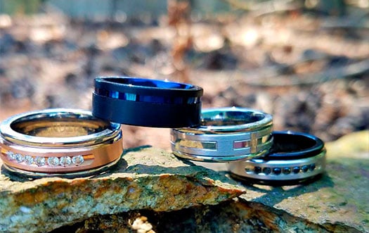 Four different kind for Men's wedding bands stacked on top or each other.